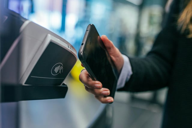 Usuario utilizando tecnología NFC en su smartphone para validar el ingreso en una lectora contactless, ilustrando sistemas de control de acceso inteligente y credenciales móviles.