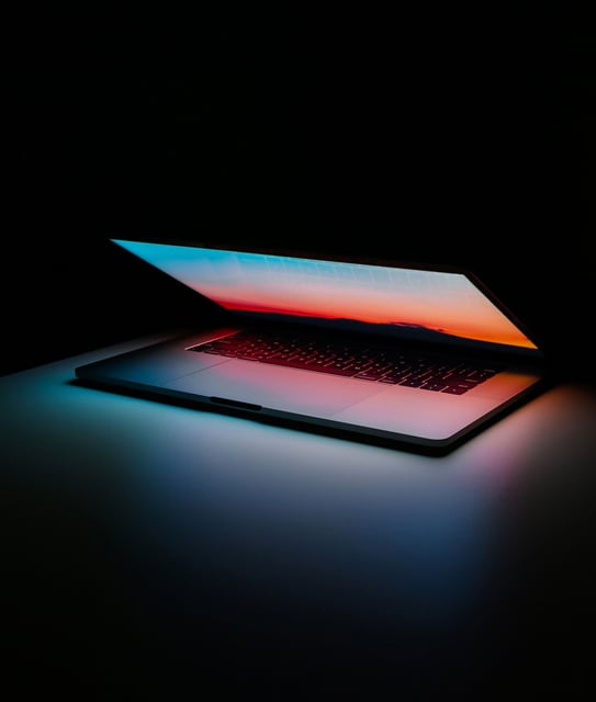 Laptop de última generación semiabierta en un entorno elegante y oscuro, ilustrando el beneficio del arrendamiento de cómputo para empresas que buscan actualizar su hardware constantemente sin descapitalizarse.