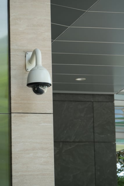 Cámara de videovigilancia tipo domo instalada en la fachada de un edificio moderno, representando los servicios de sistemas de CCTV, control de acceso y seguridad perimetral para empresas.