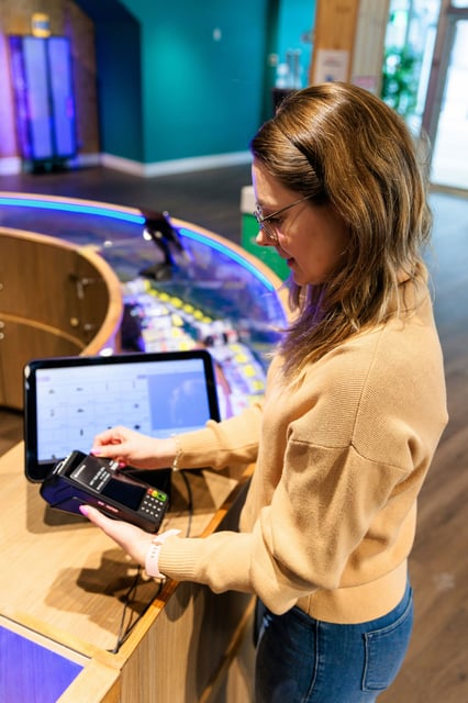 Mujer realizando un pago con tarjeta en una terminal de cobro con pantalla táctil integrada, ilustrando la rapidez y modernización del proceso de ventas con MyBusiness POS y Vorak.