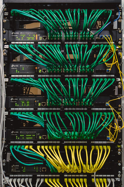Rack de telecomunicaciones con cableado estructurado e interconexión impecable de switches administrables TP-Link, representando el servicio de ordenamiento, diseño e instalación de redes corporativas.